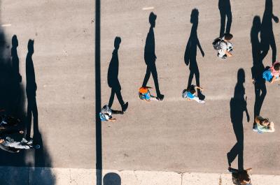 A photo of people walking with long shadows.