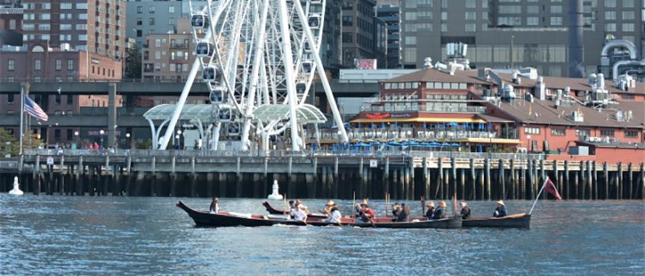 Suquamish citizens paddle two canoes past downtown Seattle.