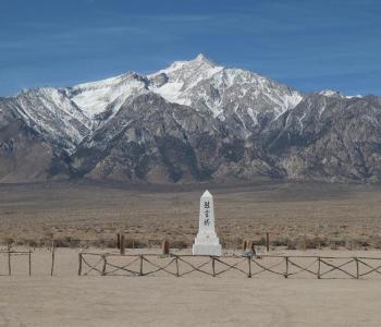 still from Manzanar Diverted: shows a japanese white stone monument in a plain in front of mountains
