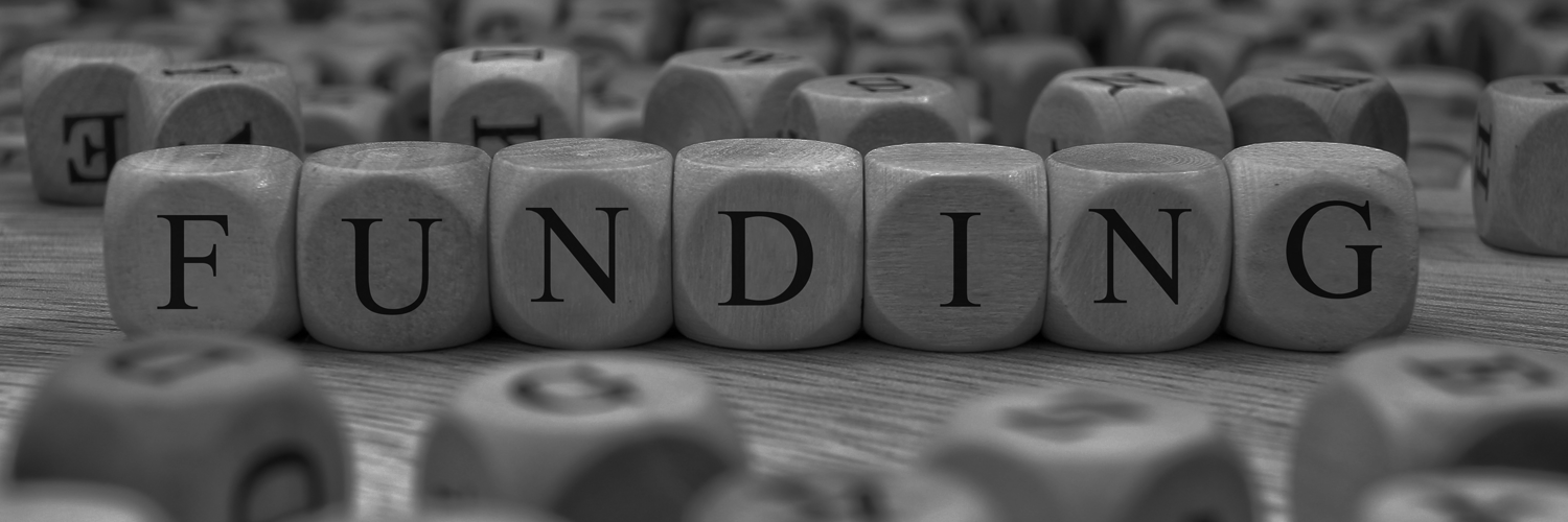 Black-and-white photo of Scrabble pieces that spell out FUNDING.