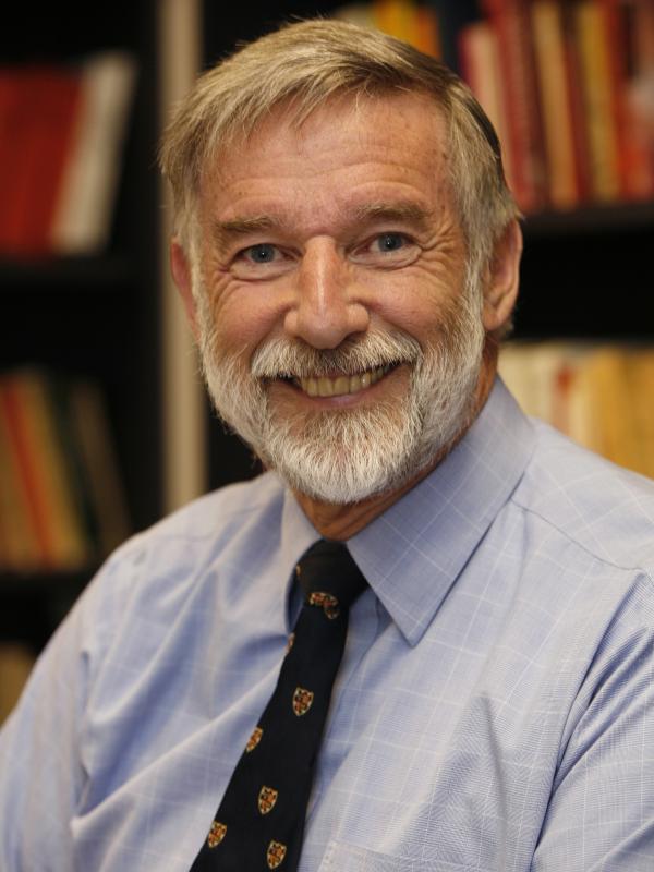 Geoffrey Parker wears a collared shirt and tie and smiles into the camera.