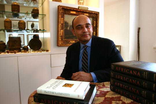 Kwame Anthony Appiah sits behind a desk with several books in front of him.