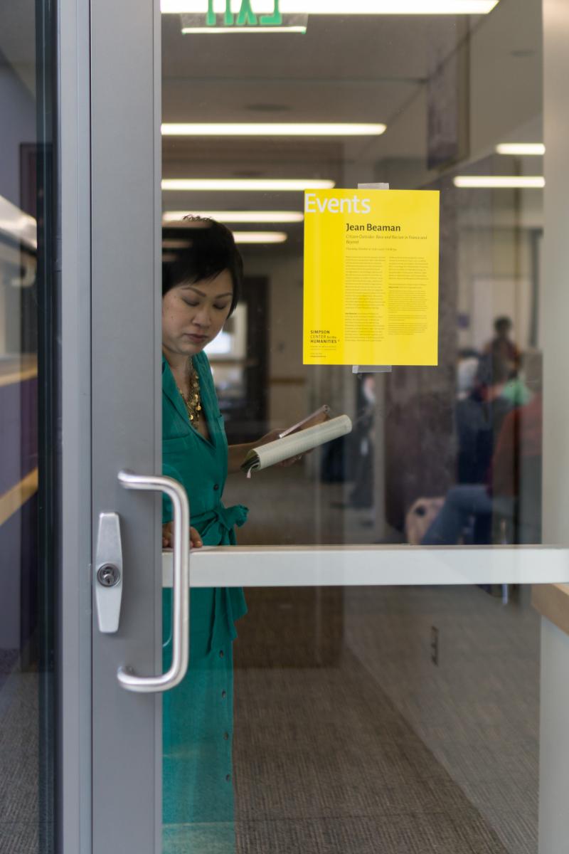 someone about to open a glass door that has a yellow event flyer on it