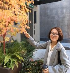 Portrait of Xin Peng standing by a golden Japanese Maple tree
