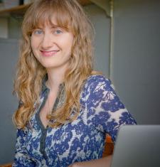 Adair Rounthwaite stands in front of a bookcase wearing a floral shirt.