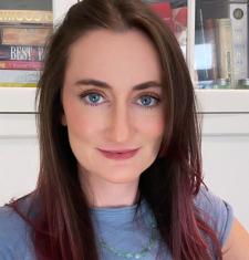 Close-up portrait of a white woman with pink and brown hair and blue eyes wearing a blue shirt