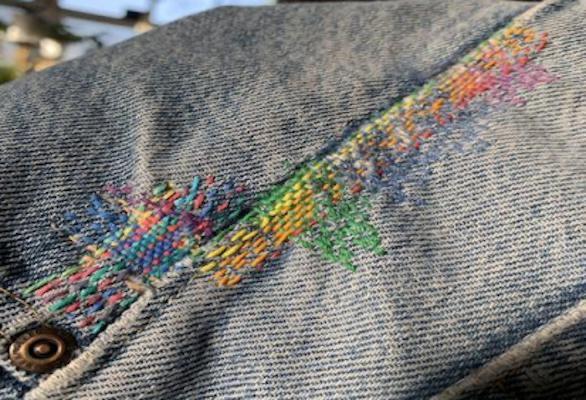 close-up of denim seam with rainbow stitching