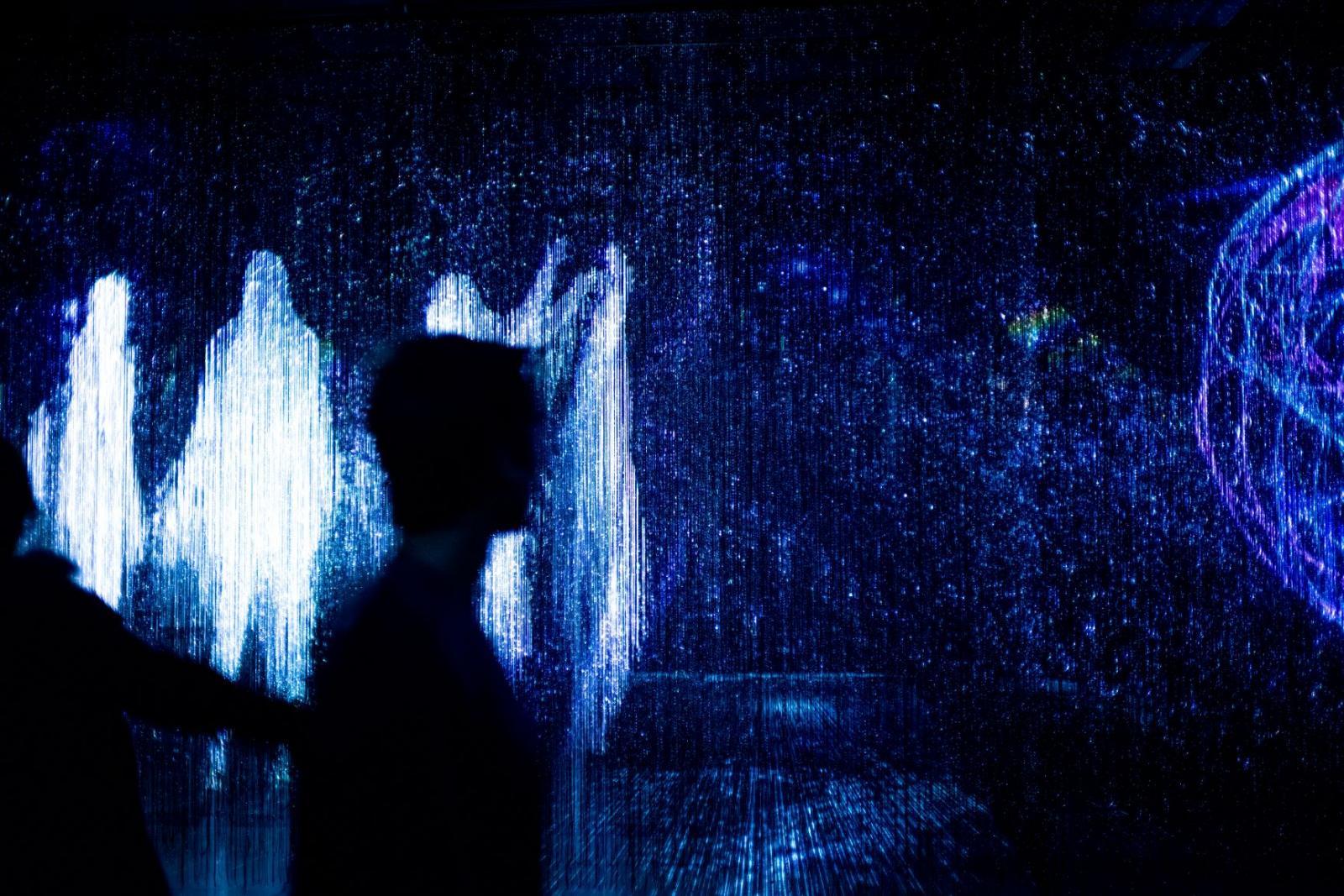 Abstract image of white ghost-like figures framing the outline of a person on a dark background.