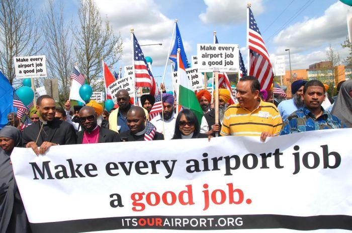 Group of protestors holding a banner that reads, "Make every airport job a good job."