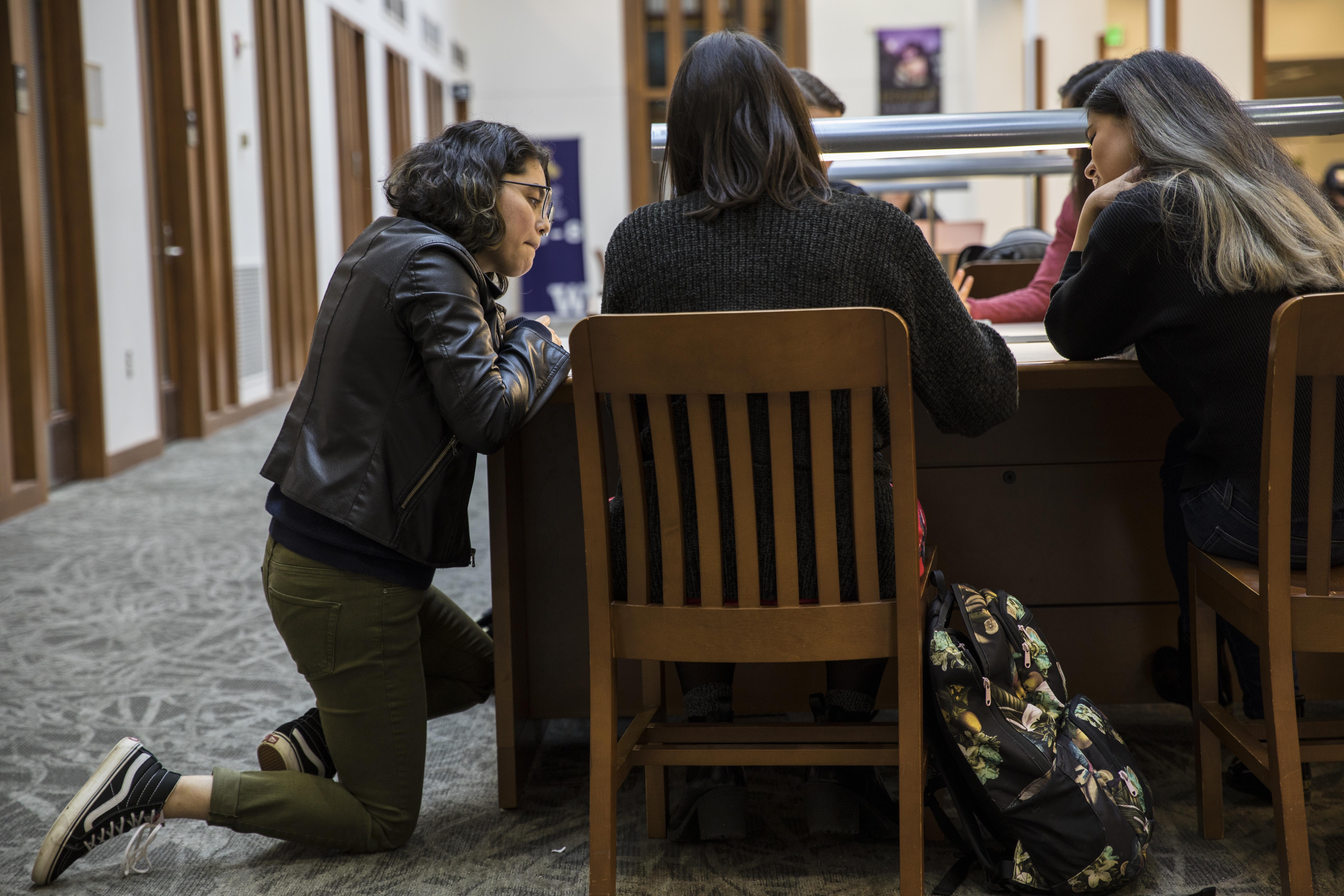 students clustered around a desk in the library
