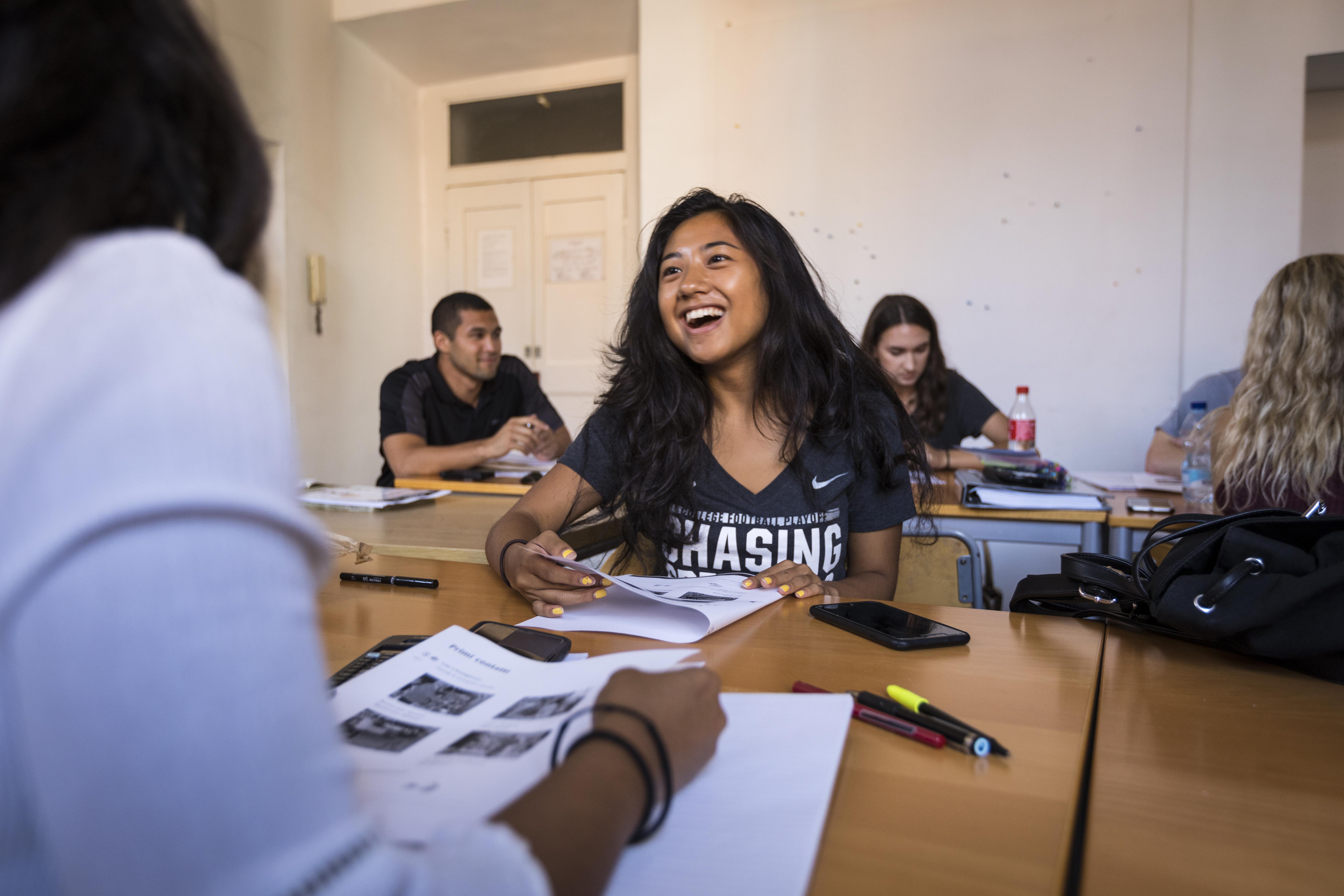 student laughing at cluster of desks with friends