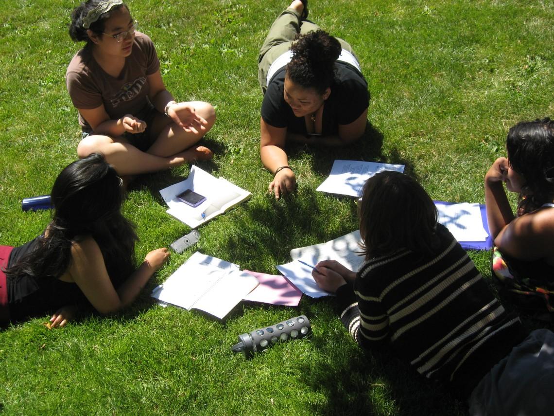 students from the institute laying on the grass in a circle with open notebooks