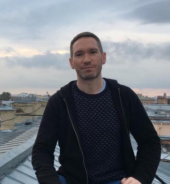 Brendan McElmeel stands on a rooftop wearing a dark shirt.