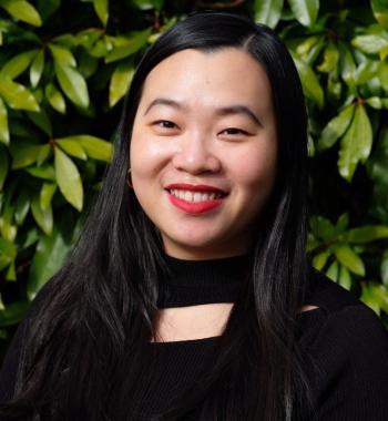 Picture of Christina Yuen Zi Chung wearing a black shirt while standing in front of foliage. 