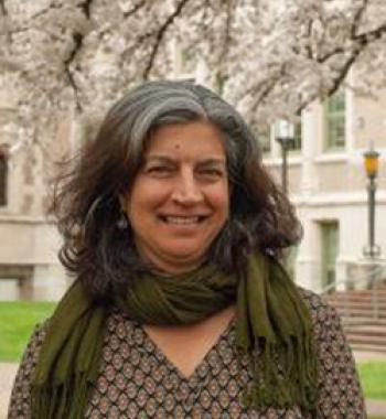 Davinder Bhowmik stands outside wearing a green scarf and patterned shirt.