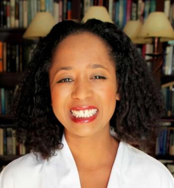 A portrait of Jasmine Mahmoud standing in front of a bookcase.