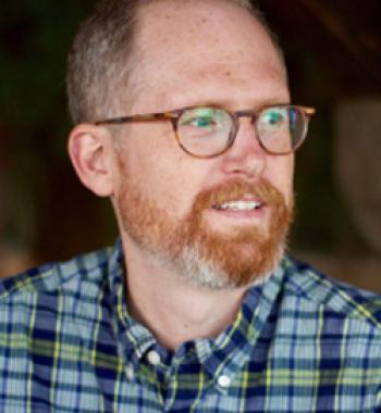 Jeffrey Knight wears a plaid shirt and glasses.