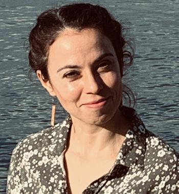 A portrait of Leah Rubinsky standing in front of a body of water.