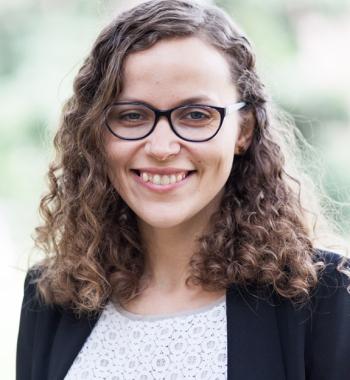 Liina-Ly Roos wears glasses, a white shirt, and a black jacket.