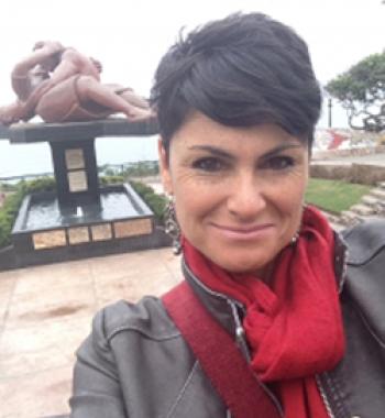 María Elena García stands outside wearing a red scarf and grey jacket.