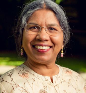 Priti Ramamurthy stands outside wearing glasses and a floral shirt.