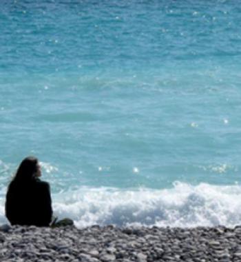 Sarah Ross sits on a beach looking toward the water.