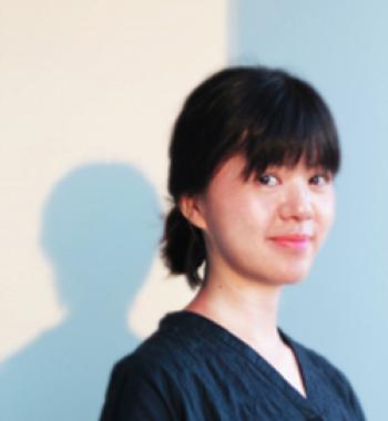 Ying-Hsiu Chou stands in front of a white wall wearing a dark shirt.