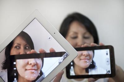 Photo is a mise en abyme with multiple digital tablets and devices fragmenting a woman.
