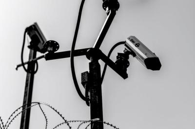 Three surveillance cameras atop barbed wire and spiked poles