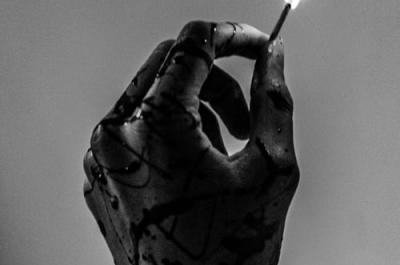A hand holds a lit match.