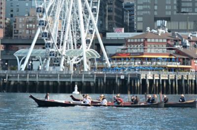 Suquamish citizens paddle two canoes past downtown Seattle.