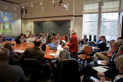 A crowd gathered around a speaker at the Simpson Center conference table