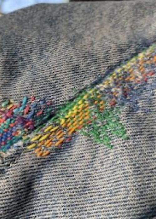 close up of a blue denim seam stitched with rainbow threads