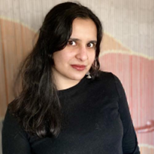 Profile picture of Nanya Jhingran wearing a black shirt and standing in front of a pink and white wall.