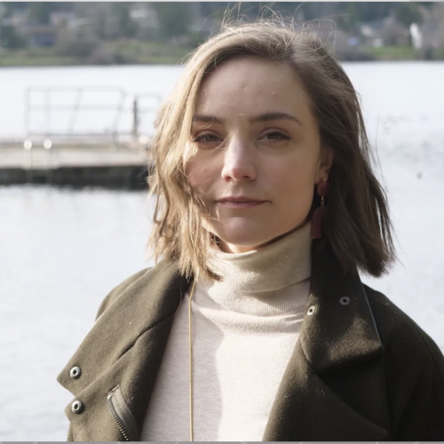 Portrait of CR Grimmer in a turtleneck and jacket with the Puget Sound behind them