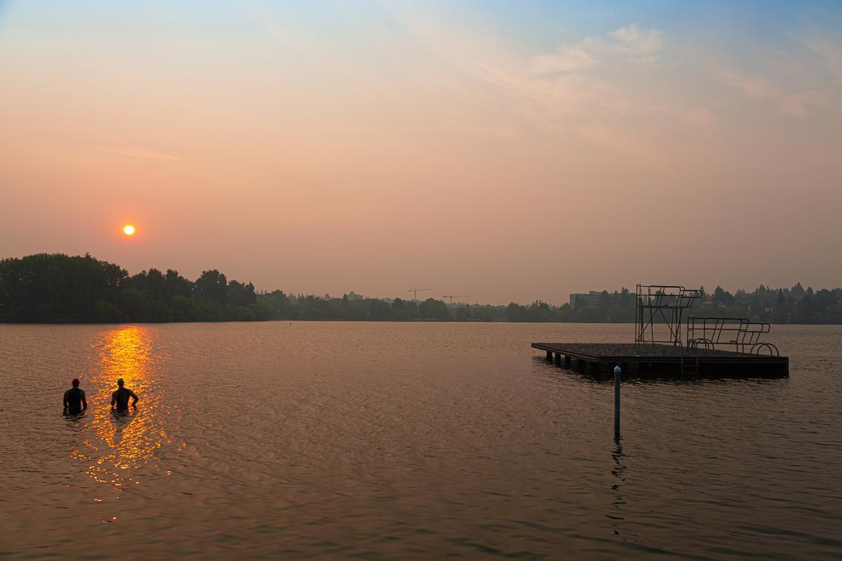 People in lake during smoky sunset