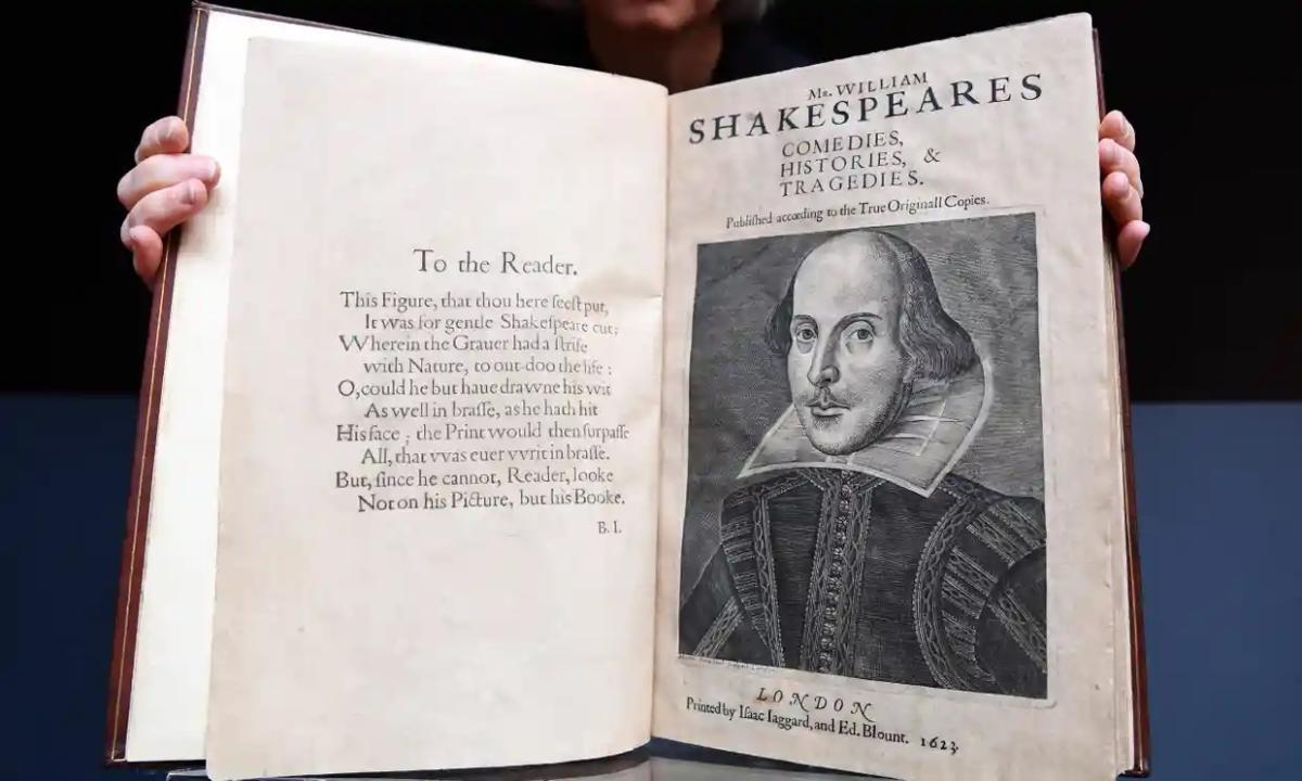 Photo of a person holding a large book open for the camera with a drawing of Shakespeare on the page.