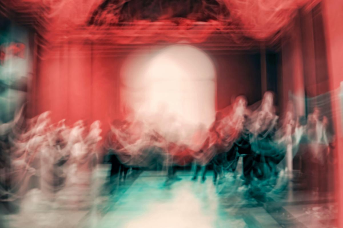 Blurred images of dancers on a stage with red curtains behind them.