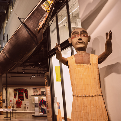 Welcome figure and canoe positioned in Burke Museum's Northwest Native Art gallery.