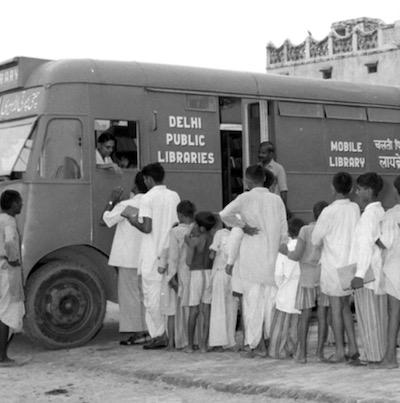 Children line up to check out books from a mobile library van in Delhi in 1957.