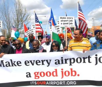 Group of protestors holding a banner that reads, "Make every airport job a good job."