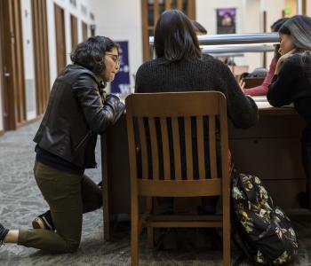 students clustered around a desk in the library