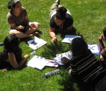 students from the institute laying on the grass in a circle with open notebooks