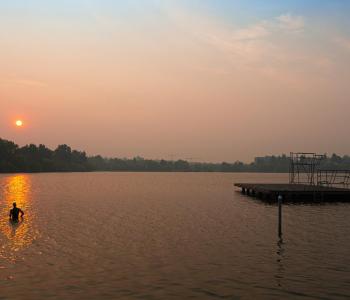 People in lake during smoky sunset