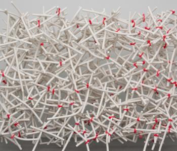 Installation art made up of white porcelain rods tied together by red plastic ties