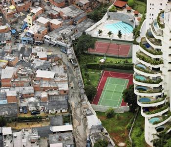 Photo of an apartment complex with tennis courts and pools walled off from an area of lower-income housing.